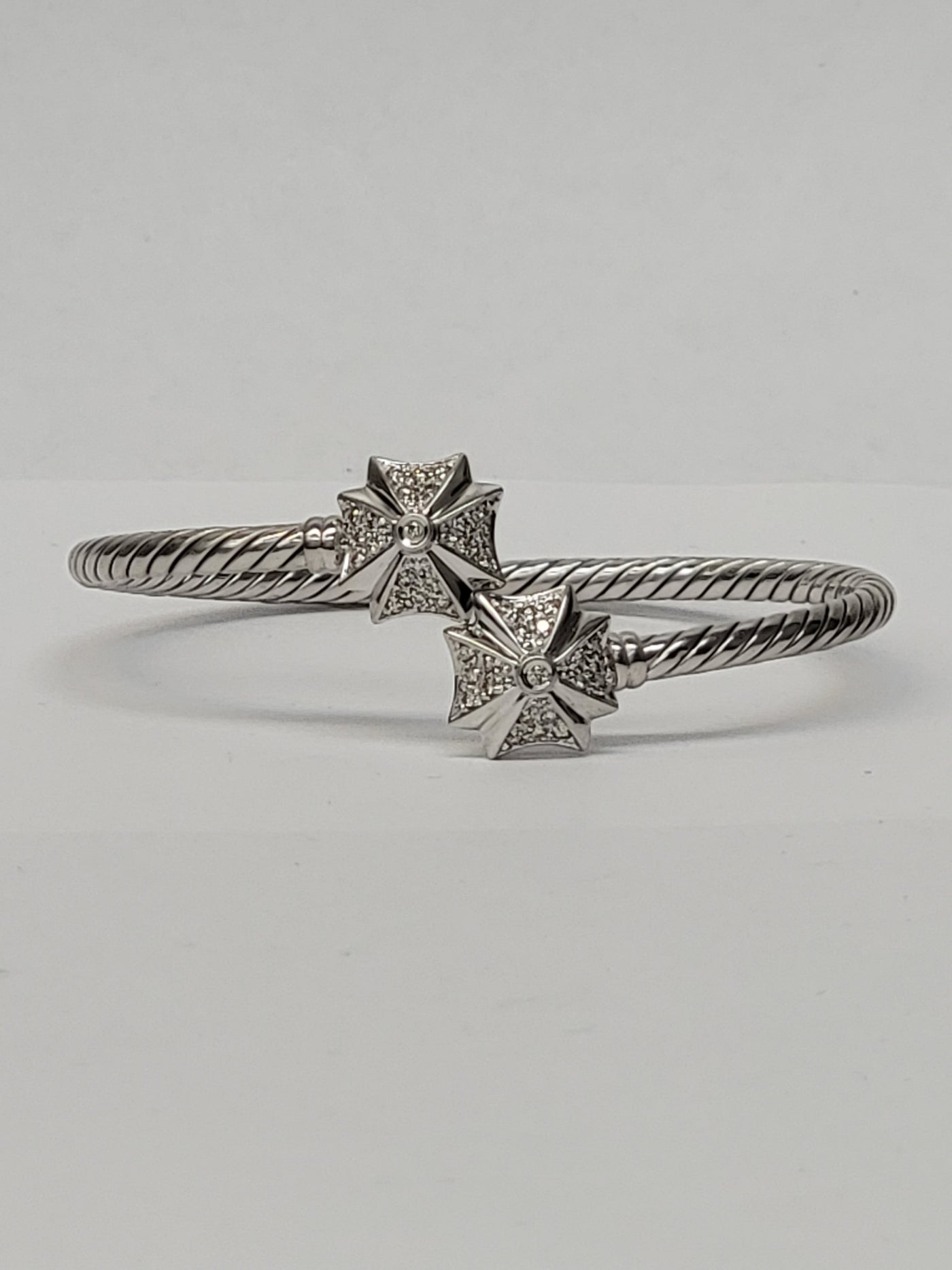 Maltese cross diamond drop earrings on display stand
